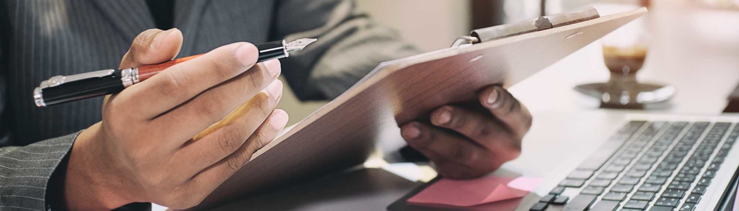 Side view of financial worker writing on clipboard