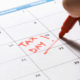 Man marking down tax day on calendar